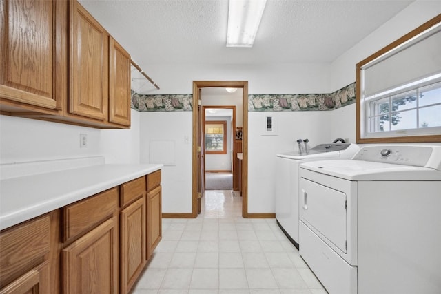 washroom with washing machine and clothes dryer, a textured ceiling, and cabinets