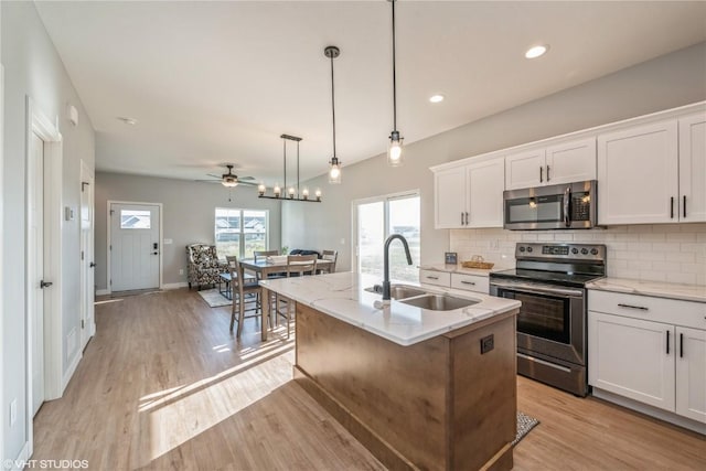 kitchen featuring pendant lighting, ceiling fan, an island with sink, appliances with stainless steel finishes, and white cabinetry