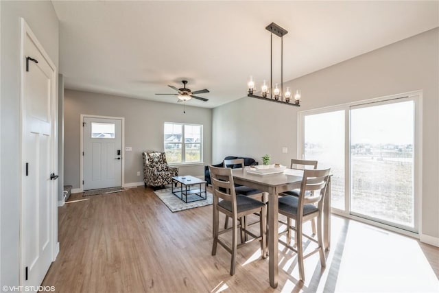 dining area featuring ceiling fan with notable chandelier and light wood-type flooring