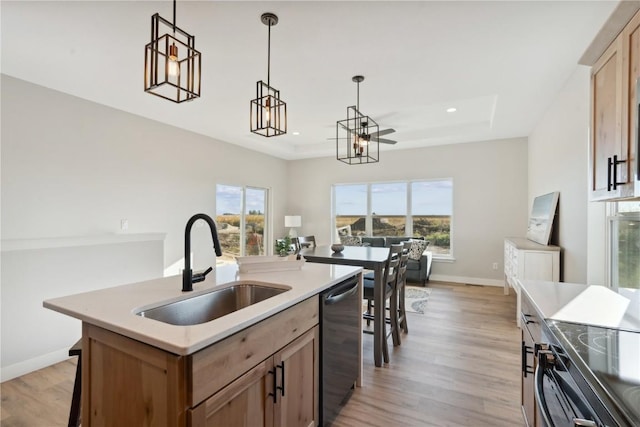 kitchen with stainless steel dishwasher, a raised ceiling, sink, and a center island with sink