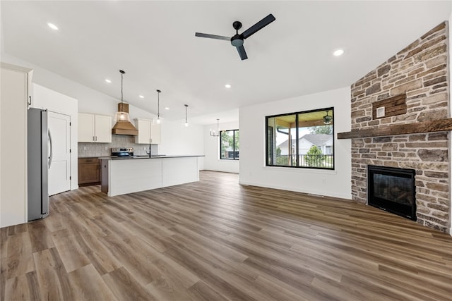 kitchen featuring ceiling fan, hanging light fixtures, white cabinetry, stainless steel appliances, and vaulted ceiling