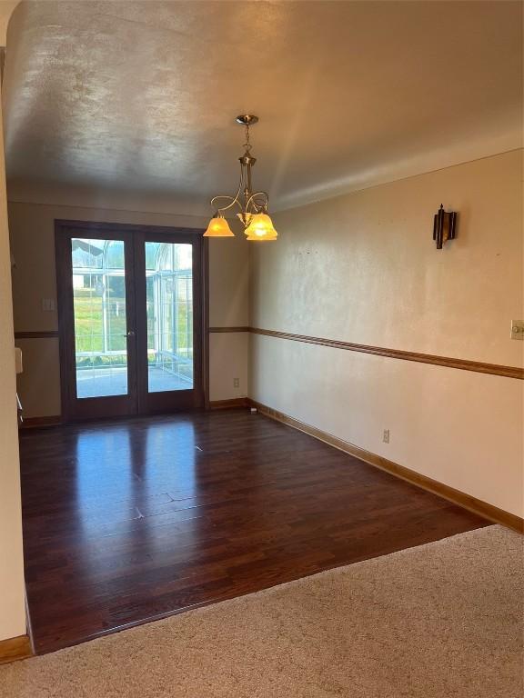 419 W 15th St, Vinton, IA 52349 - unfurnished room with baseboards, a notable chandelier, wood finished floors, and french doors