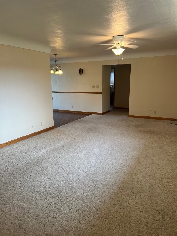 carpeted spare room with ceiling fan with notable chandelier