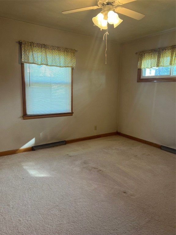 carpeted spare room featuring ceiling fan and baseboard heating