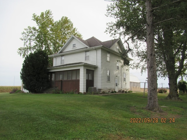 view of side of property with a lawn and a sunroom