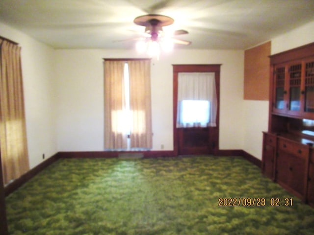 interior space featuring dark carpet and ceiling fan