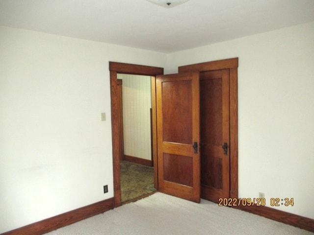 unfurnished bedroom featuring a closet and light colored carpet