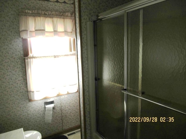 bathroom featuring a shower with shower door and toilet