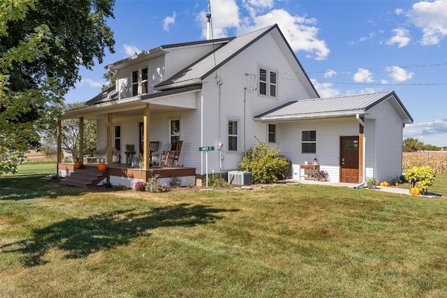 rear view of property featuring a lawn, cooling unit, and covered porch