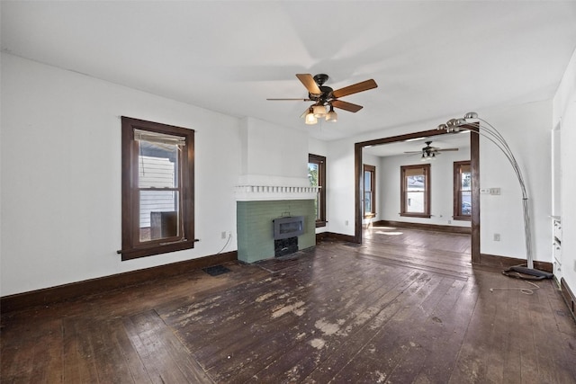 unfurnished living room with a fireplace, dark hardwood / wood-style floors, and ceiling fan