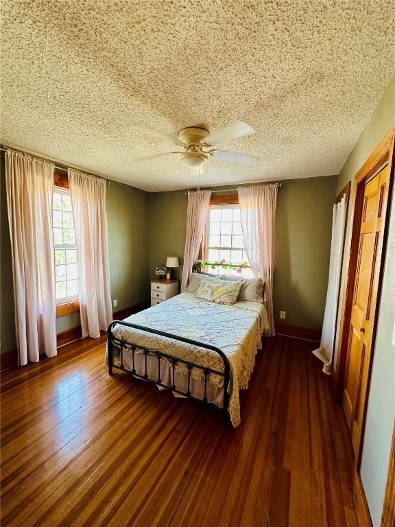 bedroom with dark wood-type flooring, ceiling fan, a textured ceiling, and multiple windows