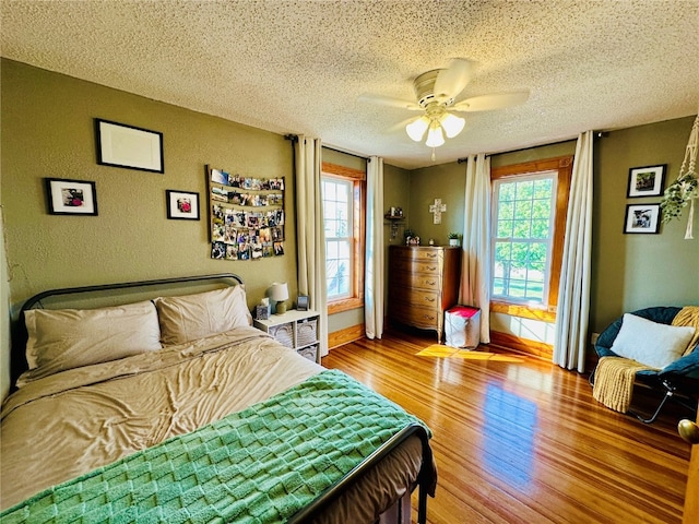 bedroom with multiple windows, a textured ceiling, hardwood / wood-style flooring, and ceiling fan