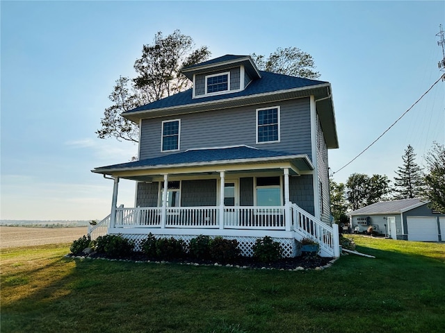 view of front facade featuring covered porch, a front lawn, an outbuilding, and a garage