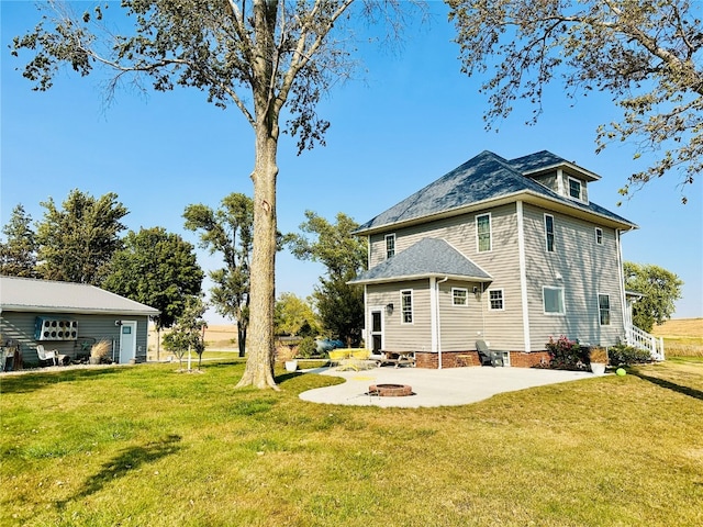 back of property featuring a lawn, a patio area, and a fire pit