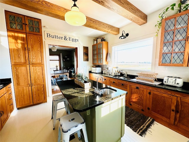 kitchen with beam ceiling, tasteful backsplash, a breakfast bar, pendant lighting, and sink