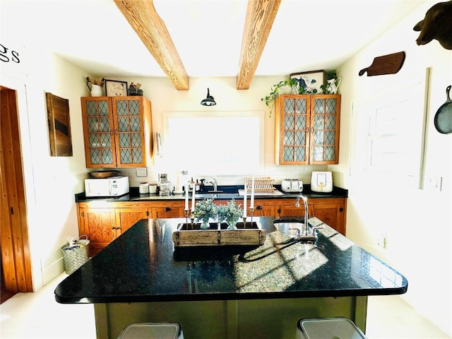 kitchen with sink, a kitchen bar, backsplash, a large island, and beamed ceiling