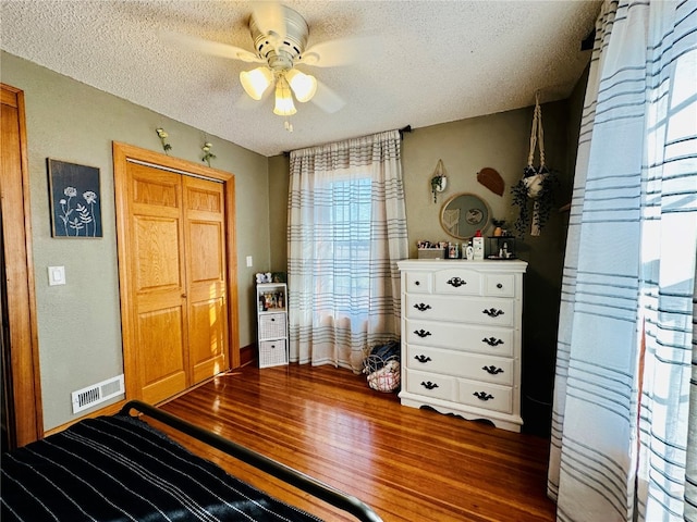 bedroom with ceiling fan, a textured ceiling, a closet, and dark hardwood / wood-style flooring