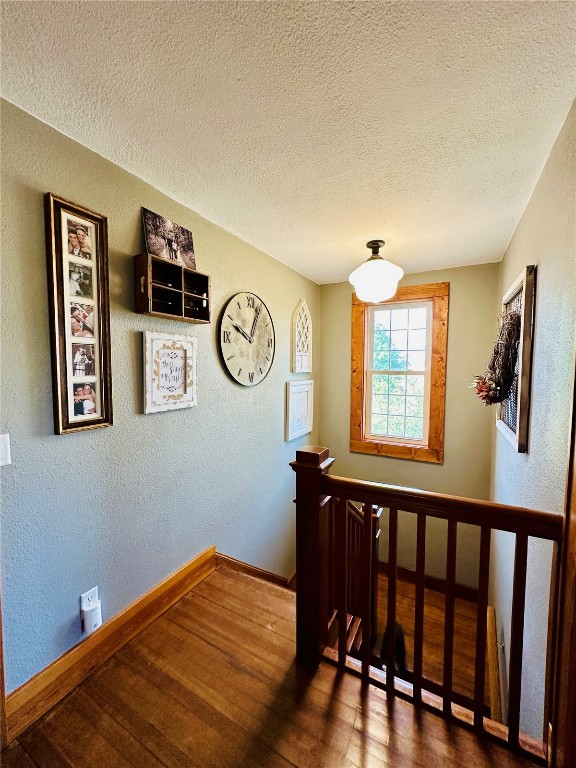 staircase featuring a textured ceiling and wood-type flooring