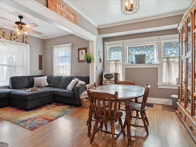 dining space featuring ceiling fan, ornamental molding, and light wood-type flooring