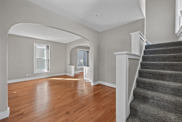 staircase featuring a textured ceiling, hardwood / wood-style flooring, and plenty of natural light