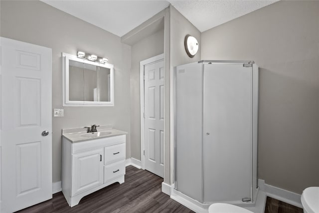 bathroom with vanity, hardwood / wood-style floors, a shower with shower door, and toilet