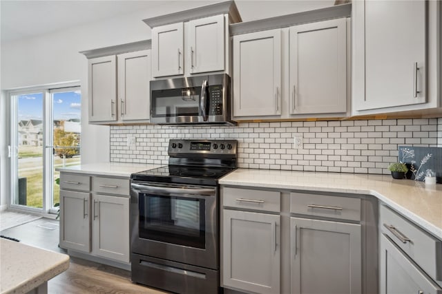 kitchen featuring appliances with stainless steel finishes, decorative backsplash, light hardwood / wood-style floors, and gray cabinets