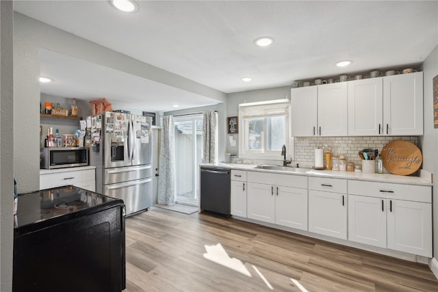 kitchen with white cabinets, light hardwood / wood-style floors, appliances with stainless steel finishes, and sink