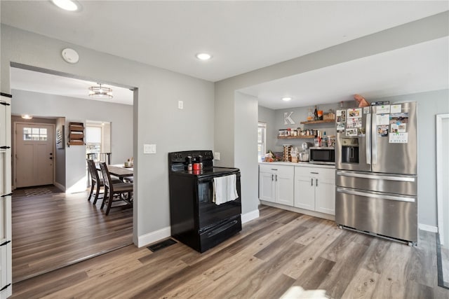 kitchen with white cabinetry, light hardwood / wood-style floors, appliances with stainless steel finishes, and a barn door