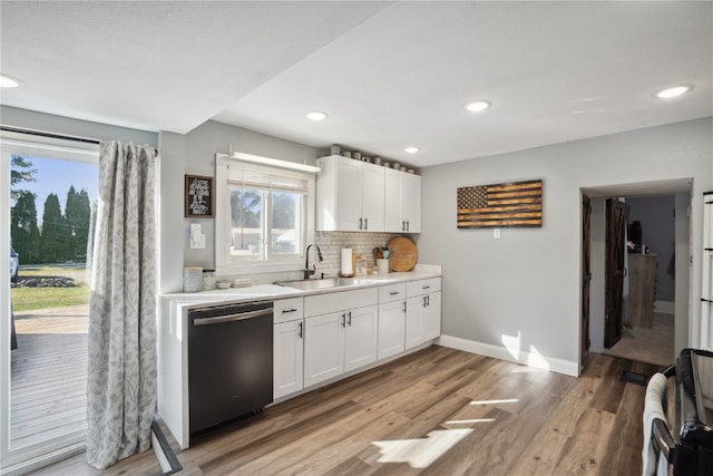 kitchen with dishwasher, light hardwood / wood-style floors, sink, white cabinetry, and backsplash