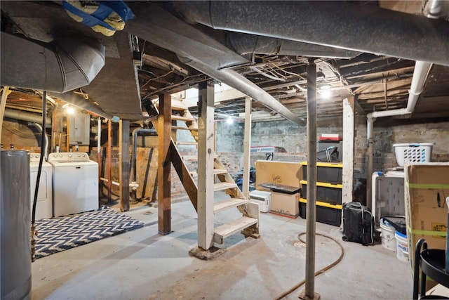 basement featuring washing machine and dryer, electric panel, and gas water heater