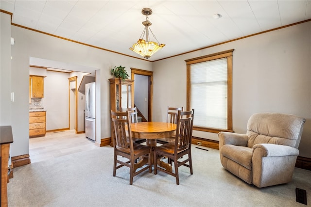 dining room with crown molding, light hardwood / wood-style floors, and a chandelier