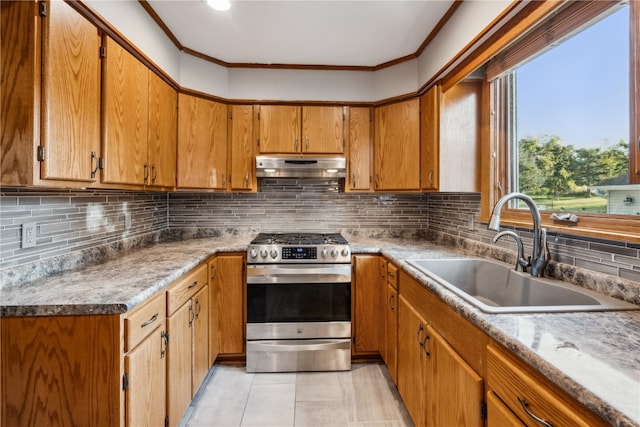 kitchen with sink, backsplash, light tile patterned floors, crown molding, and stainless steel range