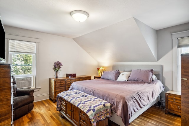 bedroom with light hardwood / wood-style flooring, cooling unit, and vaulted ceiling