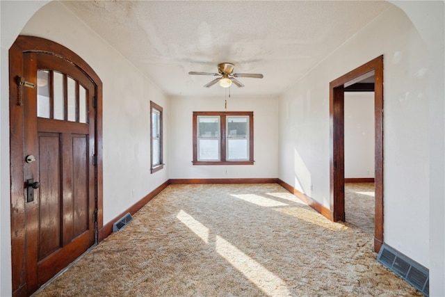 carpeted foyer featuring a textured ceiling and ceiling fan