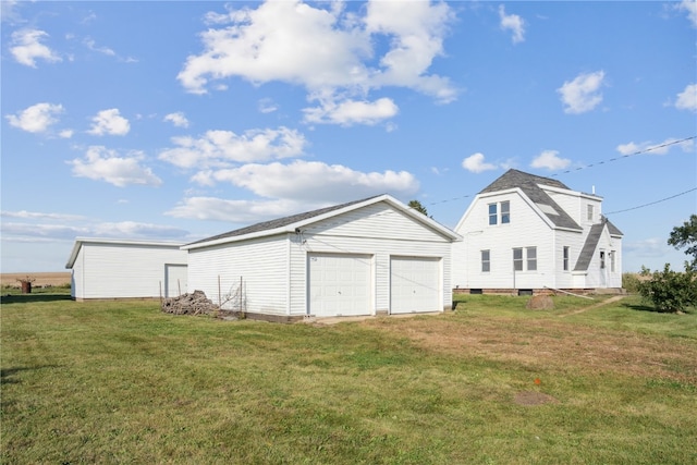 back of property featuring a lawn, an outbuilding, and a garage