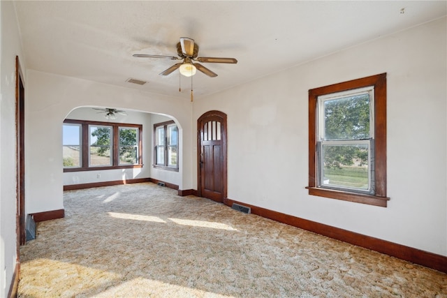 foyer entrance with ceiling fan, plenty of natural light, and carpet floors