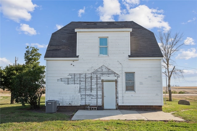 rear view of house with cooling unit and a yard