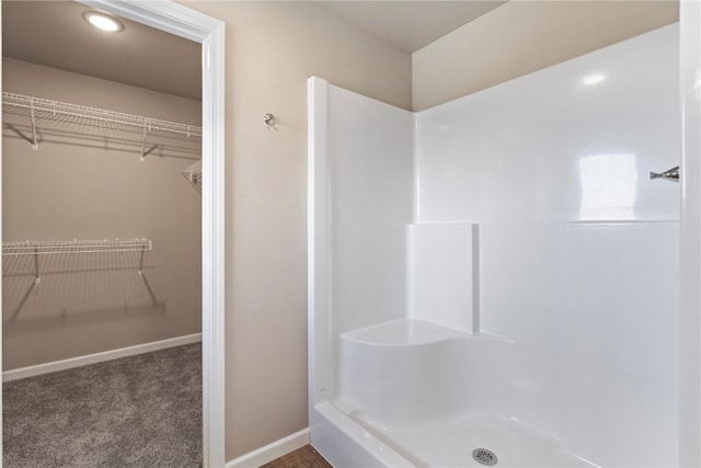 full bathroom featuring a walk in closet, baseboards, and walk in shower