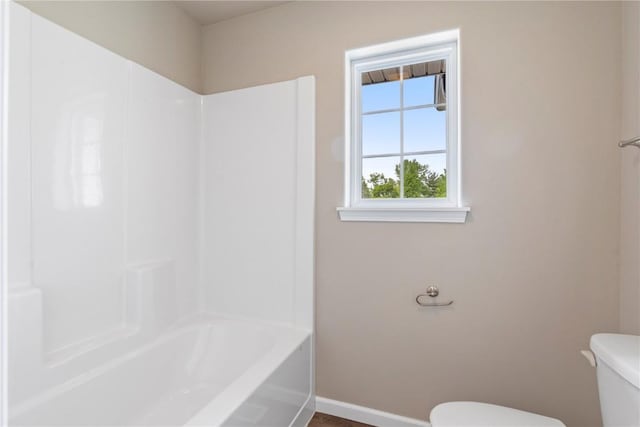 full bath featuring toilet, baseboards, and shower / washtub combination