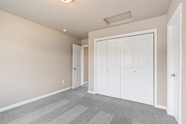 unfurnished bedroom featuring carpet floors, attic access, baseboards, and a closet