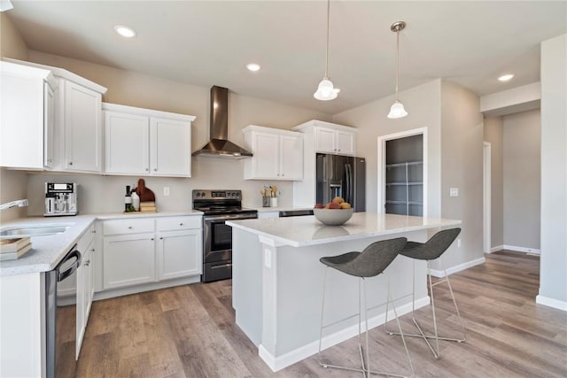 kitchen featuring white cabinetry, a kitchen island, a sink, wall chimney range hood, and black appliances