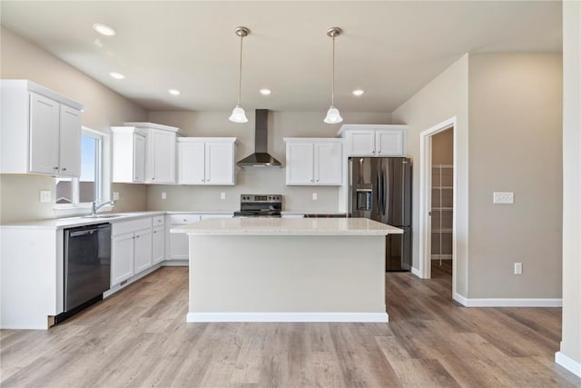 kitchen featuring appliances with stainless steel finishes, white cabinets, a kitchen island, and wall chimney exhaust hood