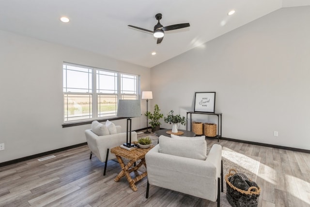 living room featuring ceiling fan, light hardwood / wood-style floors, and vaulted ceiling