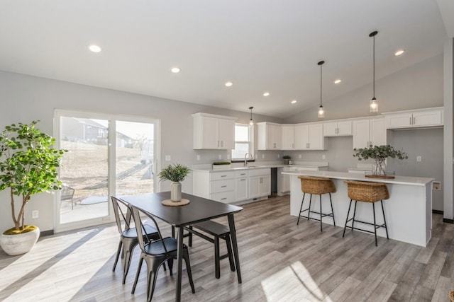 dining space with vaulted ceiling, sink, and light hardwood / wood-style flooring