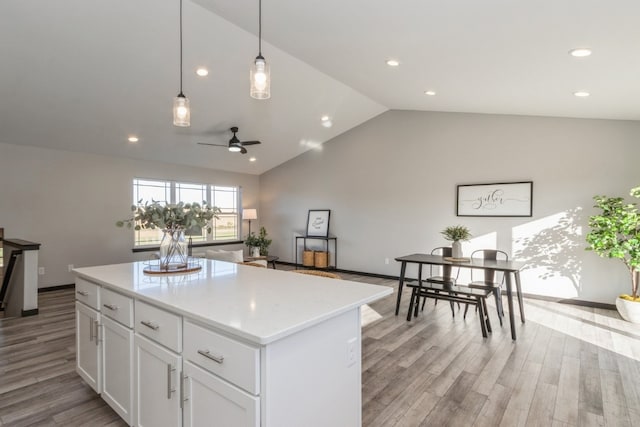 kitchen featuring white cabinets, pendant lighting, lofted ceiling, a kitchen island, and light hardwood / wood-style floors