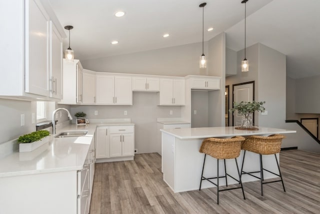 kitchen with white cabinets, light hardwood / wood-style flooring, sink, and a kitchen island