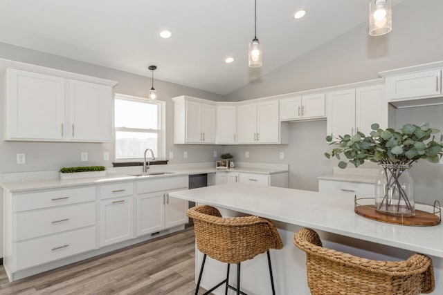 kitchen with lofted ceiling, white cabinetry, and sink