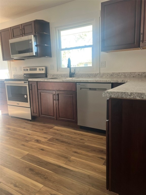 kitchen featuring dark brown cabinets, hardwood / wood-style flooring, appliances with stainless steel finishes, and sink