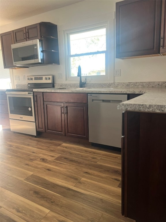 kitchen featuring dark brown cabinets, wood-type flooring, appliances with stainless steel finishes, and sink