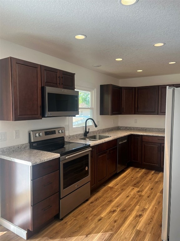 kitchen with a textured ceiling, light hardwood / wood-style floors, sink, and stainless steel appliances